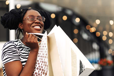 Young african woman in shopping, Smiling woman with bags, enjoying shopping for Christmas, mall, consumerism, shopping, lifestyle conceptの写真素材