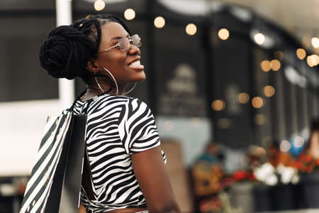 Beautiful happy African woman, in the mall with shopping bags, woman doing Christmas shoppingの写真素材