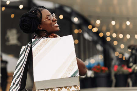 Beautiful happy African woman, in the mall with shopping bags, woman doing Christmas shoppingの写真素材