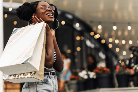 Beautiful happy African woman, in the mall with shopping bags, woman doing Christmas shoppingの写真素材