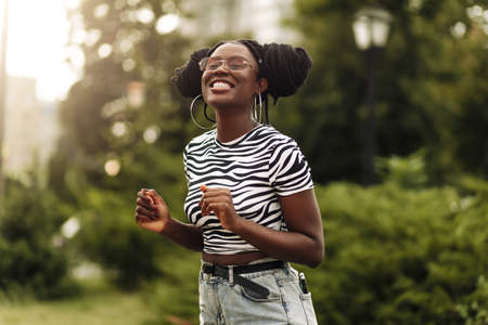 Happy black african woman walking down the street, beautiful young woman enjoying summer vacation, cheerful woman looking at camera smilingの写真素材