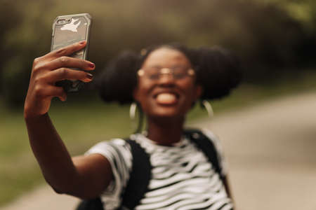 Smiling black american woman taking selfie on cell phone, outdoorsの写真素材