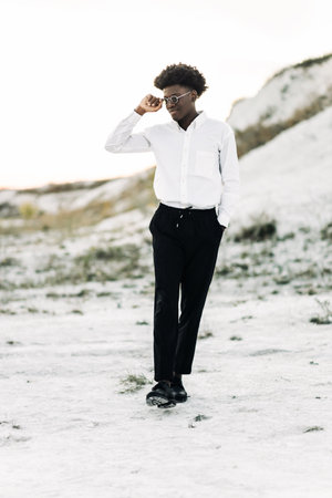 Handsome fashionable african american hipster man, in stylish sunglasses and in a white shirt, posing on the street, fashion posing, fashion, styleの写真素材