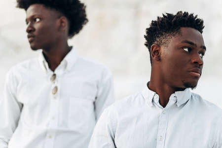 Two trendy black men, fashion portrait of African American male models, in white shirts, outdoors against the background of chalk mountains and rocksの写真素材