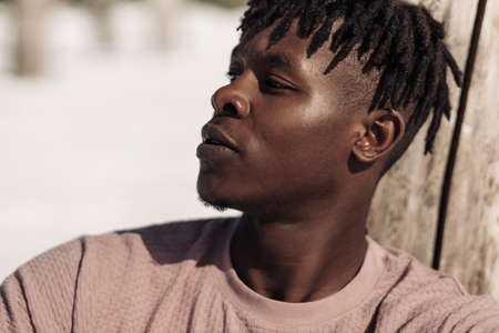 Portrait of a contented happy black man, has a warm wide smile, wears a casual white t-shirt,...