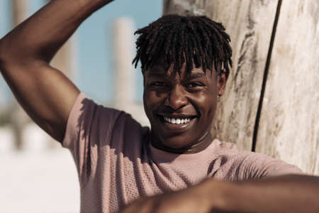 Portrait of a contented happy black man, has a warm wide smile, wears a casual white t-shirt, outdoors, People and positive emotions conceptの写真素材