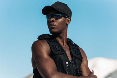Portrait of African American man, fitness athlete, in sportswear, with muscular body, outdoors,...