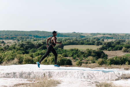 African American fitness men, in sportswear, running along the rocky path on the mountain, muscular man climbing the mountain outdoorsの写真素材