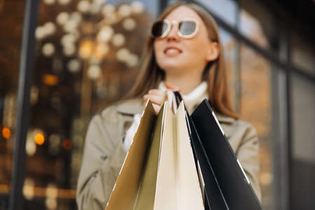 close-up of shopping bags in hands, in front of a glass building, and lights. autumn theme: shopping.の写真素材