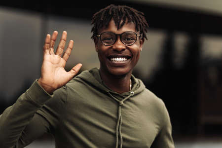 Happy african american man, wearing glasses looking at camera, cheerful black man posing outdoors in cityの写真素材
