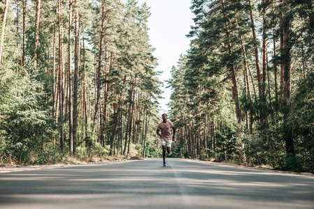 African American fitness man, runner running on trail in the forest, Young man running on the road, Man with headphones running in the park in the morning, Healthy lifestyle conceptの写真素材