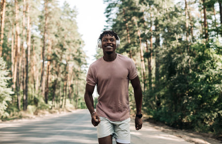 Handsome sporty African man in sportswear exercising in the park and listening to music with headphones, Sport concept, Healthy lifestyle, motivationの写真素材