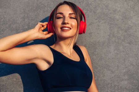 Excited happy sporty woman, wearing wireless headphones, listening to music and smiling, posing...
