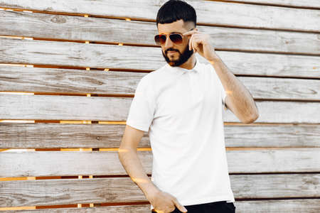 Portrait stylish handsome man in sunglasses, in casual clothes posing, isolated on isolated wooden background outdoors. lifestyle concept. Copy space for copyの写真素材