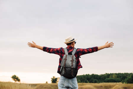 Happy free man standing alone with raised arms during a beautiful sunrise in the morning. Outdoor...