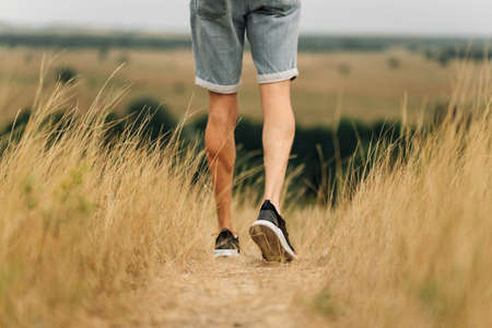 man with a backpack on a country walk on a summer day. Young people hiking in the countryside, outdoors at sunset, traveler wearing hat and sunglassesの写真素材