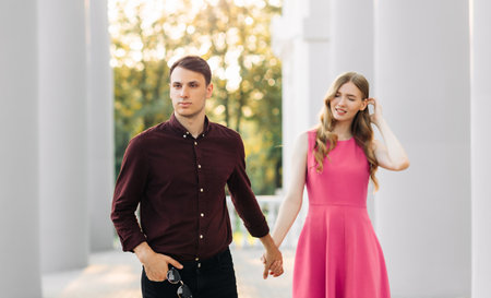 Image of a happy beautiful young couple in love, dating in the city outdoors. Romantic couple walking in the city holding hands, celebrating Valentine's Day, February 14の写真素材