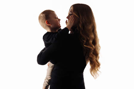 happy family. Mom holds her son in her arms, The boy kisses mom and hugs on an isolated white background.Caring loving mom hugs her child. concept of family, motherhood, mother's dayの写真素材