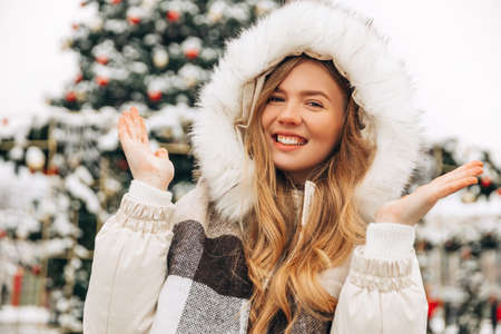 Festive Christmas fair, winter holidays concept: happy smiling woman in a scarf, catching...