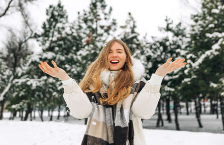 Close up portrait of beautiful happy smiling woman with long hair in white coat and warm scarf....