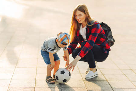 Happy family play football in summer, Mother and son play and run in the park on a beautiful morning. A boy kicks football while playing with his family. family conceptの写真素材