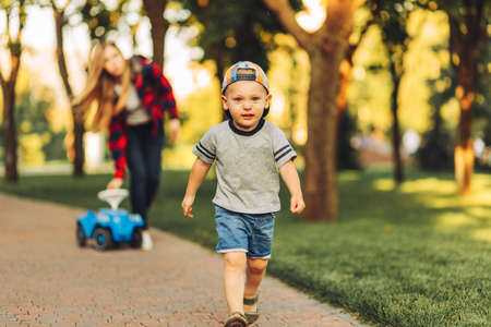 mother with a capricious crying son walks in the park on a summer sunny day. A sad and frustrated child is crying in the street. Tantrums and whims of children. Children's emotions and whimsの写真素材