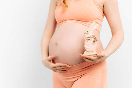pregnant woman holds her hands on her stomach on a white background. Pregnancy, motherhood, preparation and expectation concept. Close-up, Beautiful tender mood photo of pregnancy.の写真素材