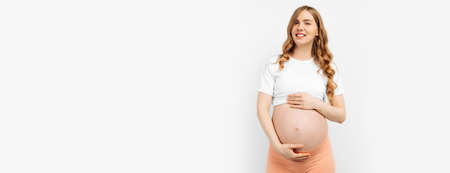 Pregnant happy beautiful woman touches her belly. Pregnant mom caressing her belly and smiling close...