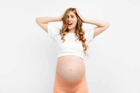 I'm afraid. Portrait of frightened unsure pregnant woman standing isolated on white studio background. Nervous excited woman experiences before childbirth Human emotions, facial expression conceptの写真素材