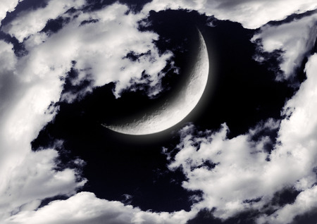 The moon in the night sky in cloudsの写真素材