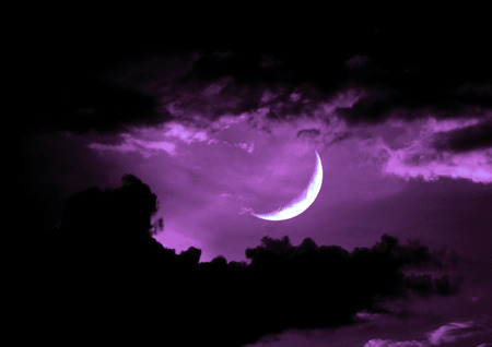 The moon in the night sky in cloudsの写真素材