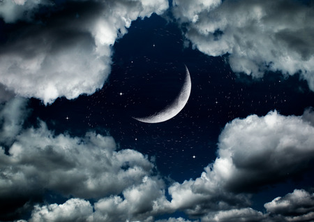 The moon in the night sky in cloudsの写真素材