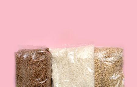 three bags with groats on a pink background. Victim assistance concept. Buckwheat, rice, barleyの写真素材