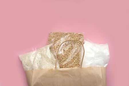 Food supply crisis food stock quarantine period isolation on a pink background. Rice, barley, sugar. Food Delivery, Donation, Coronavirus Quarantine. In a paper bag.の写真素材
