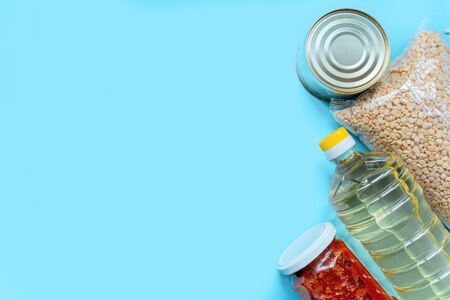Food supply crisis food stock quarantine period isolation on a blue background. Canned food, barley, oil, tomato paste. Food Delivery, Donation, Coronavirus Quarantine.の写真素材