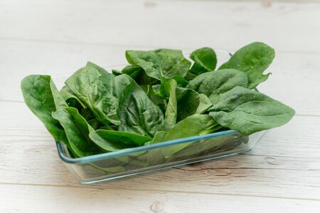 Spinach in a transparent bowl on wooden tableの写真素材