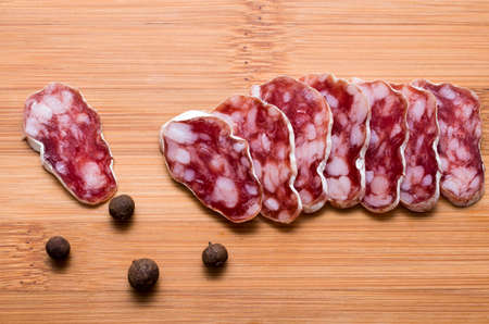 Smoked sausage cut on a wooden board with pepers