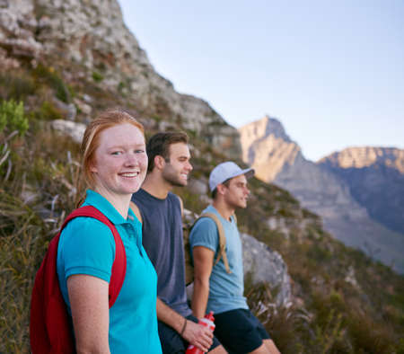 Pretty female student resting with friends while hiking on a nature trail