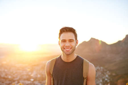 Handsome young man on an early morning nature hike smiling confidently at the cameraの写真素材