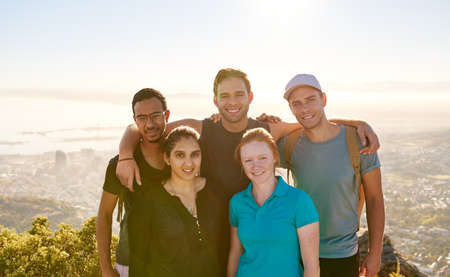 Smiling group of student friends posing for a portrait while on a hike together in natureの写真素材