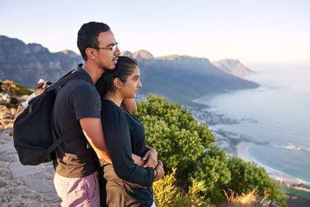 Loving young Indian couple taking in the view while on a mountain nature hike