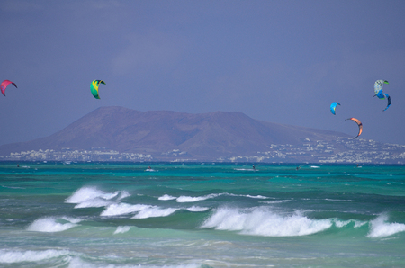 some kitesurfers riding on the wave of ocean near the island Fuereteventuraの写真素材
