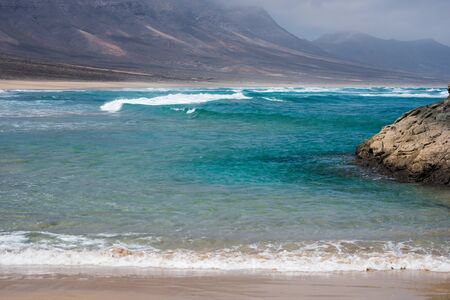 Nature poster. Beach and ocean. Fuerteventura. Cofete. Mountain near the beach with sand and blue oceanの写真素材