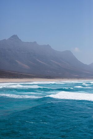 Nature poster. Beach and ocean. Fuerteventura. Cofete. Mountain near the beach with sand and blue...