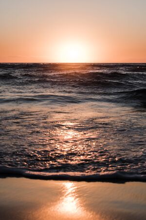 nature poster.  orange sunset at the beach with wave of ocean and light reflectionの写真素材