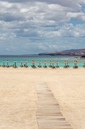 poster. seascape. sand beach with umbrellas and chair. relax resort with wood bridgeの写真素材