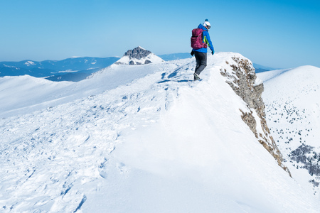 Young woman on a trip in the snow-covered Alps, dangerous stretch on the ridge of the mountain