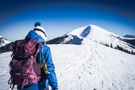 Young woman walking on snowy European mountainsの写真素材