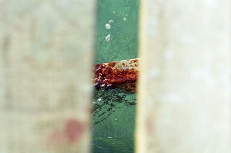 detail of a rusty metal under a wooden walkway on the beachの写真素材