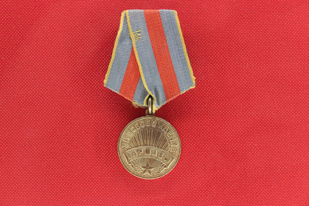 An old retro medal on a red background, a reward for work and courage. Rarity. High quality photoの写真素材